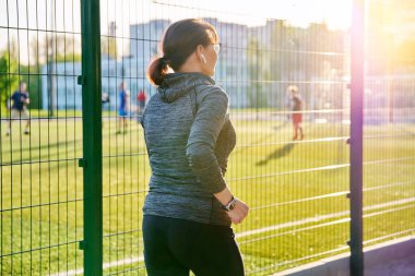 Olgun aktif bir kadın stadyumun yanında koşuyor.