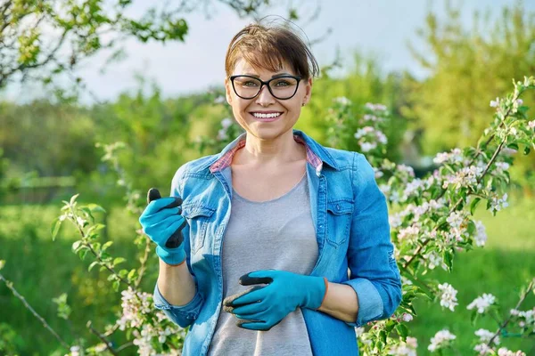 Portrait of beautiful middle aged woman in blooming spring garden. — Stok Foto