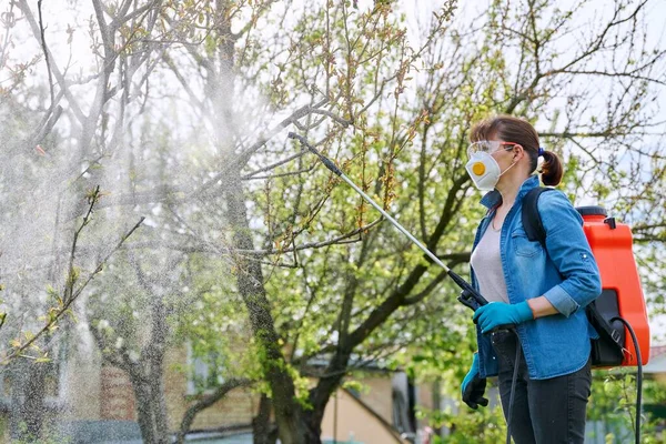 Woman with backpack garden spray gun under pressure handling peach tree — Zdjęcie stockowe