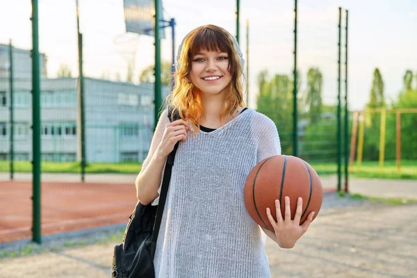 美しい女性の学生のヘッドフォンでバックパック保持バスケットボールボール — ストック写真