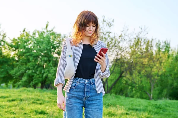 Outdoor portrait of trendy young red-haired girl with smartphone in hand — 스톡 사진