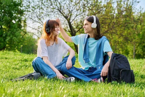 เพื่อนสองคน ชายและหญิง อายุ 17 อายุ 18 นั่งอยู่บนหญ้า — ภาพถ่ายสต็อก