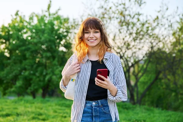 Retrato al aire libre de la joven de moda pelirroja con teléfono inteligente en la mano — Foto de Stock