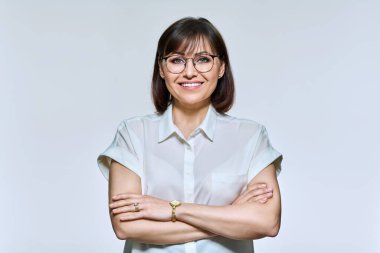 Portrait of positive confident middle aged woman looking at camera, on light background