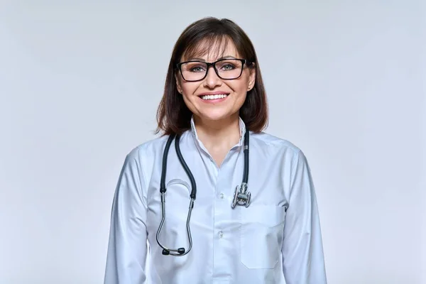 Retrato de mulher madura médico com estetoscópio no fundo do estúdio de luz — Fotografia de Stock