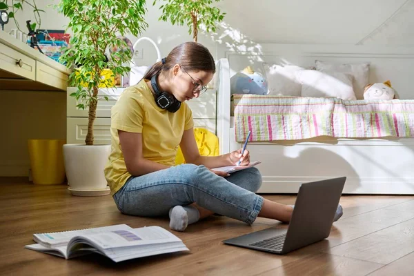 Ragazza adolescente con gli occhiali che studia a casa con un computer portatile — Foto Stock