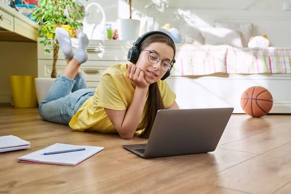 Ragazza adolescente con gli occhiali che studia a casa con un computer portatile — Foto Stock