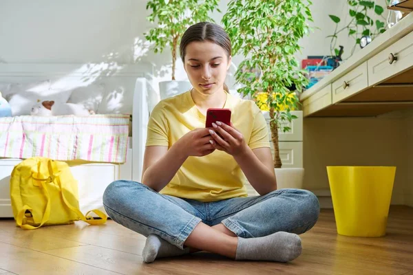 Teenagerin nutzt Smartphone, ruht zu Hause auf dem Fußboden im Zimmer — Stockfoto