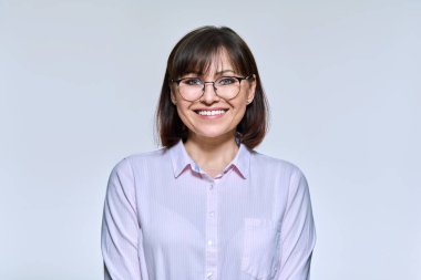 Portrait of mature beautiful woman looking at camera, on light studio background. Confident successful middle aged woman with glasses. Lifestyle, emotions, beauty, age, people concept