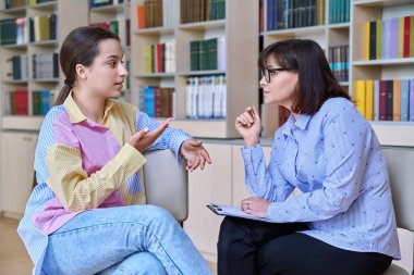 Psikolog, öğretmen, davranış, lise danışmanı kütüphanede, ofiste genç öğrencilere danışmanlık yapıyor. Psikolojik yardım, sosyal hizmet, akıl sağlığı, ergenlik, gençlik psikolojisi