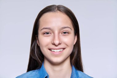Dişleriyle gülümseyen çekici bir genç kızın parlak stüdyo arka planında, kameraya bakan portresi. Sağlıklı cilt kılı dişleri, gençlik gençliği güzellik anlayışı olan güzel bir genç kız.