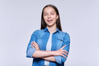 Işık stüdyosunun arka planında kameraya bakan gülümseyen genç bir kızın portresi. Kollarını kavuşturmuş kendinden emin bir lise öğrencisi. Eğitim gençlik gençlik gençlik güzellik kavramı