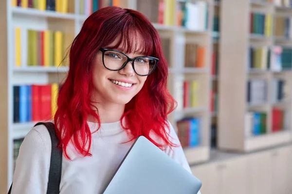 带着手提电脑背包的女学生的肖像 在图书馆看相机 漂亮的时尚女郎 红头发 戴眼镜 笑着带着牙齿 — 图库照片