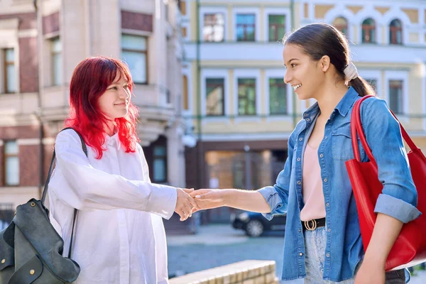 Meeting of two teenage girls friends, outdoor on city street. Happy joyful fashionable females embrace greeting. Joy happiness together, friendship communication lifestyle, youth concept