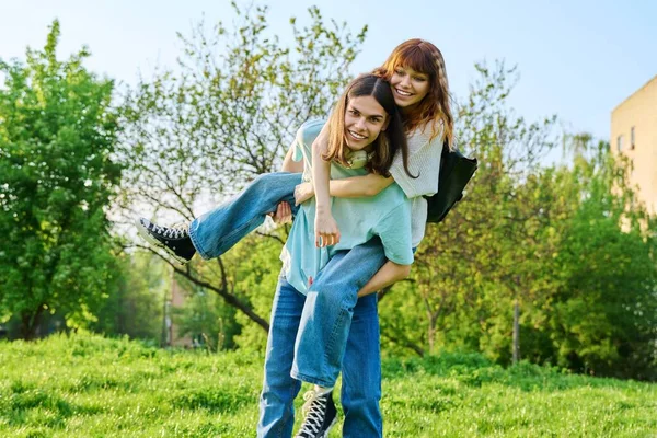 一緒に屋外で楽しいティーンエイジャーを持つ幸せのカップル 若い十代の男性と女性が芝生の上で公園で笑っている 若者の概念 — ストック写真