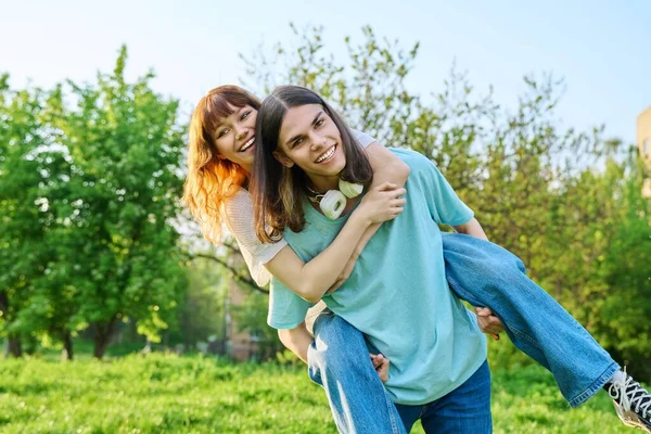 一緒に屋外で楽しいティーンエイジャーを持つ幸せのカップル 若い十代の男性と女性が芝生の上で公園で笑っている 若者の概念 — ストック写真