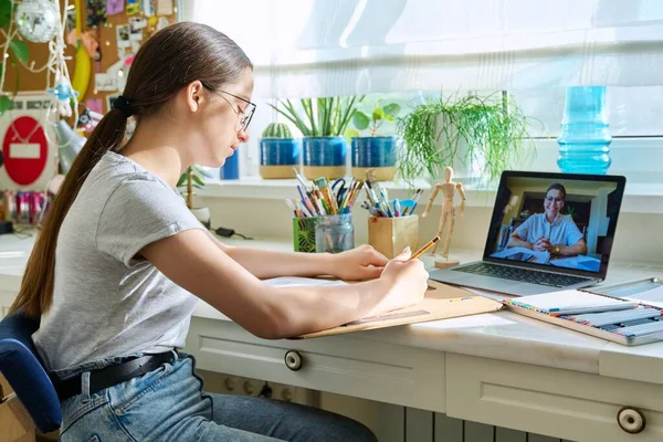 Online drawing lesson, teenage girl having video call conference chat with teacher sitting at table at home. Young creative art student. Creativity technology education e-learning adolescence concept