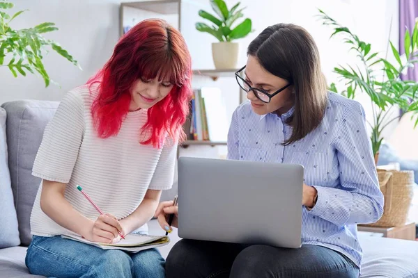 Female teacher teaches student teenage girl, sitting together on couch in office, educational counseling, using laptop. Education, knowledge, individual training, adolescence concept
