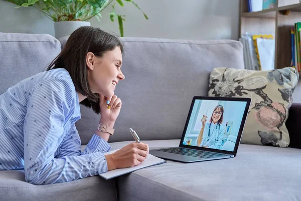 Young woman making video call with doctor, online meet consultation at home. Female using laptop for chat conference, doctor on screen. Technology, medicine, health care, people concept