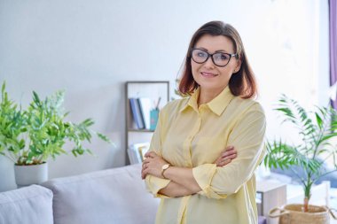 Ofiste kendinden emin orta yaşlı bir iş kadınının portresi. Kadın psikolog, danışman, uzman, kollarını kavuşturup kameraya bakan yönetici. İş, meslek, terapi, olgun insanlar konsepti