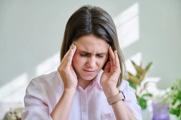 Young stressed woman with headache holding her head with her hands. Health, migraine, depression, negative, problems, people concept