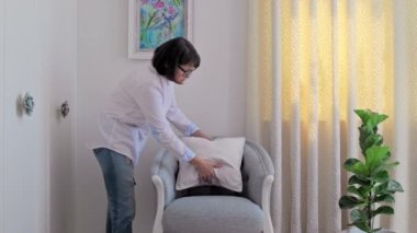 A woman decorating blue armchair with velvet beige cushion. Home interior decoration, style and design, upholstery, furniture concept