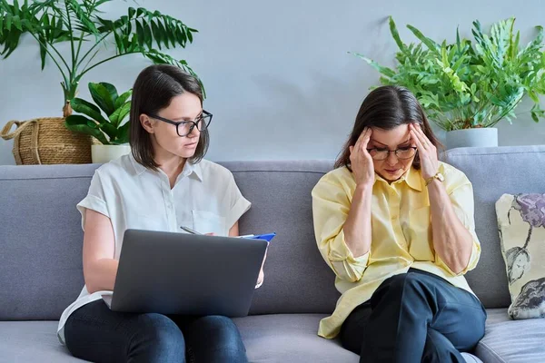 Middle-aged woman in individual therapy session in psychologist office. Counselor talking, taking notes with mature patient. Psychology, mental health, counseling, social work, psychotherapy concept