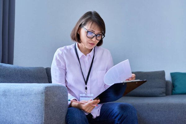 Female psychologist with clipboard working sitting on the couch in the office. Psychology, social service, psychotherapy, counseling, therapy, treatment, mental health concept