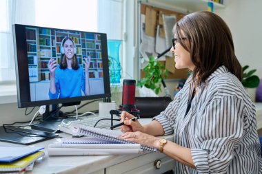 Female teacher giving video lesson to guy student. Middle aged tutor in home office talking to student on conference video call using computer. Online learning, technology, e-education, elearning