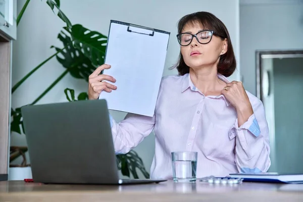 Middle-aged woman suffering from heat, overheated, cooled by fan and fan. First symptoms of menopause, age-related changes, health problems, use of vitamins, drugs, hormones to relieve