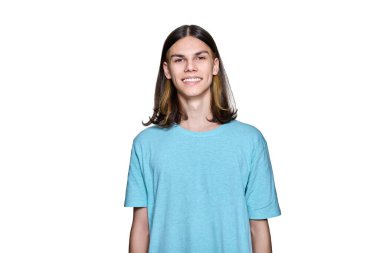 Portrait of smiling teenage guy looking at camera on white isolated background. Handsome young male with long hair hairstyle posing in studio. Youth, students, people concept