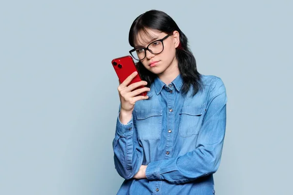 Serious Teenage Girl Glasses Smartphone Looking Screen Gray Color Background — Stok Foto