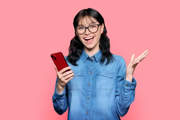 Surprised Teenage Girl Looking Smartphone Screen Pink Color Studio Background — Zdjęcie stockowe