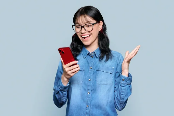 Surprised Teenage Girl Looking Smartphone Screen Gray Color Studio Background —  Fotos de Stock
