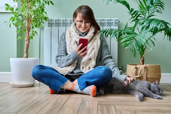 Middle Aged Woman Resting Home Warm Clothes Using Smartphone Warming — Stockfoto