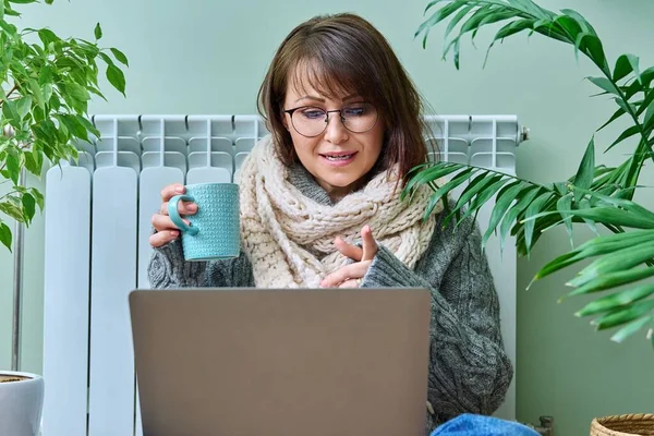 Middle Aged Female Warm Clothes Warming Heating Radiator Using Laptop — ストック写真