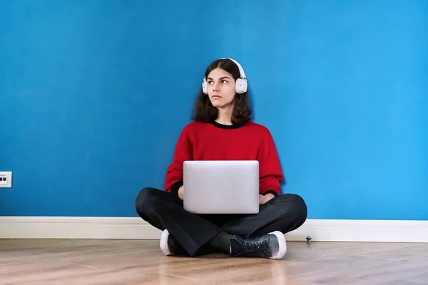 年轻的学生戴着耳机 带着笔记本电脑 坐在地板上蓝色背景 Lifestyle Youth Technology Leisure Music Education Young — 图库照片