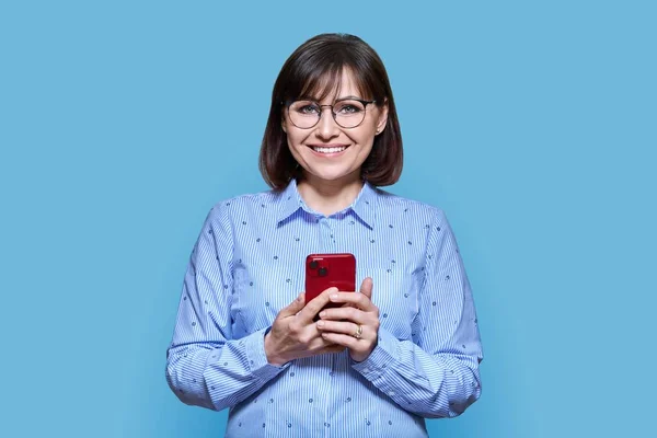 Portrait Middle Aged Woman Phone Hands Looking Camera Blue Background — 图库照片