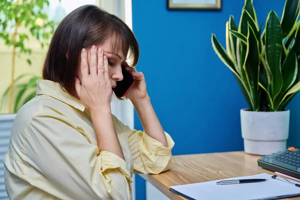 Sad middle aged woman talking on the phone. Upset mature female having difficult conversation, bad news, problems, depression, stress, pain