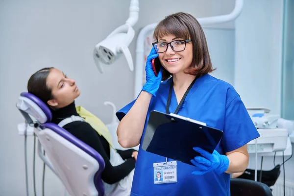 Dentist doctor nurse in the office talking on the phone. Dentistry, hygiene, treatment, dental health care concept