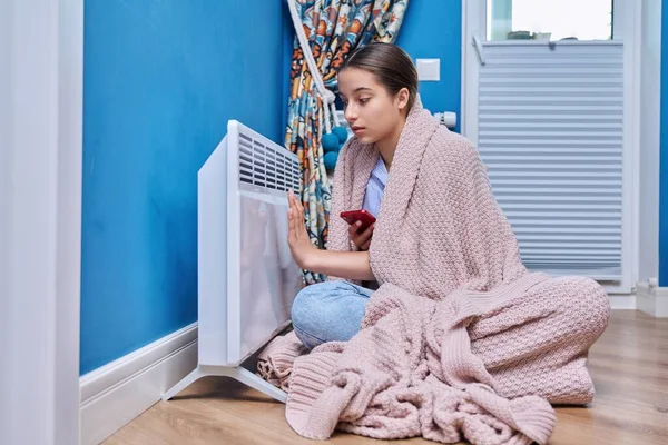 年轻的女性坐在家里电热器旁边 少女在毛毯下取暖 取暖季节 寒秋冬季概念 — 图库照片