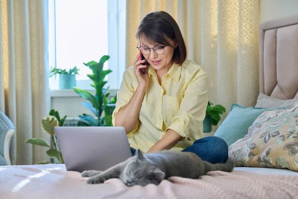 Middle Aged Woman Sitting Bed Laptop Cat Talking Phone Home — Fotografia de Stock