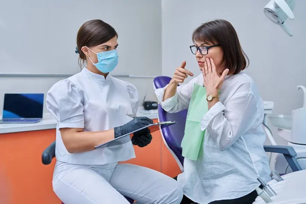 Dentystka Pacjentka Klinice Stomatologicznej Pielęgniarka Pisząca Notatniku Kobieta Średnim Wieku — Zdjęcie stockowe