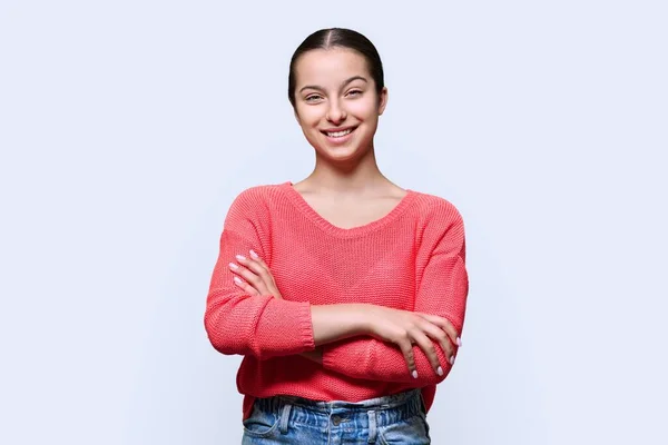 照片上的少女微笑着看着相机在光工作室的背景 有自信的少女 双臂交叉 红红的 青少年 青少年15 16岁的概念 — 图库照片