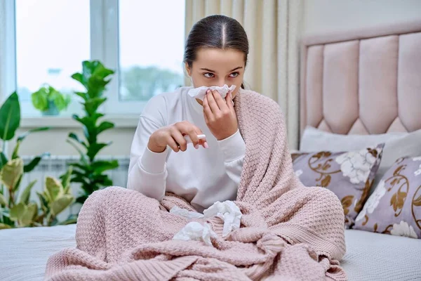 年轻的少女坐在床上 流鼻涕的药水滴在床上 打喷嚏进入组织 掩埋她的鼻子 鼻炎流鼻涕 流感季节 — 图库照片