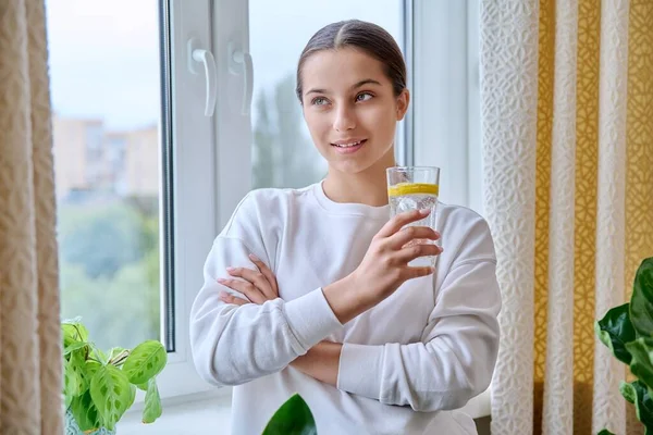 Tonårstjej Med Ett Glas Vatten Med Citron Tittar Kameran Hemma — Stockfoto