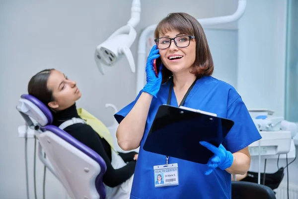 Dentist doctor nurse in the office talking on the phone. Dentistry, hygiene, treatment, medicine, dental health care concept