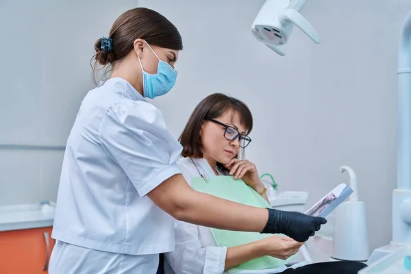 Vrouwelijke Dokter Tandarts Praat Met Middelbare Leeftijd Vrouw Patiënt Tandartsstoel — Stockfoto