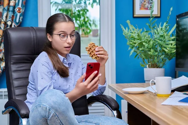 Adolescente Assise Sur Fauteuil Près Ordinateur Regardant Dans Smartphone Mangeant — Photo