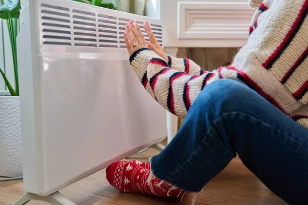 在电热散热器附近 一名女性手足的特写正在升温 温暖的秋冬 家庭生活方式理念 — 图库照片
